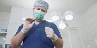 医生戴着无菌白手套和口罩在医院检查医疗器械。在诊所里，身着职业装的外科医生正在检查手上的夹