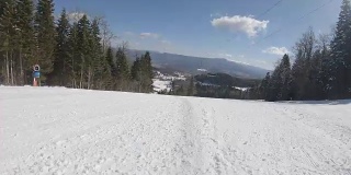 在阳光明媚的天气里，滑雪者沿着斜坡快速地滑下滑雪道
