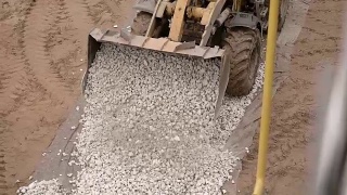 近距离拍摄在一个金属勺上，重型机械卸下小石子、卵石，铺在路上，以便再把沥青铺在那里视频素材模板下载
