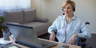 坐在轮椅上用笔记本电脑工作的资深女商人，在线视频会议