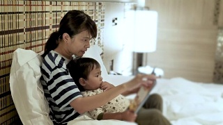 亚洲母亲和孩子，在睡觉前看书。视频素材模板下载