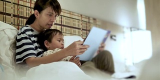 亚洲母亲和孩子，在睡觉前看书。