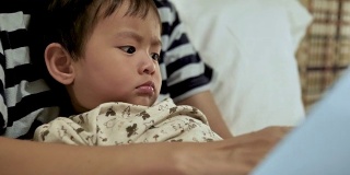 亚洲母亲和儿子在床上看书