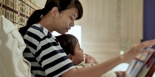 亚洲母亲和孩子，在睡觉前看书。