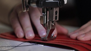 近距离拍摄的主人的手，谁使用缝纫机创造针在一个皮革钱包，针慢慢穿透材料视频素材模板下载