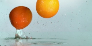 橙子碰到橙汁表面，切成两半。慢动作镜头