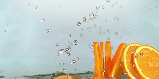 橙子碰到橙汁表面，切成两半。慢动作镜头