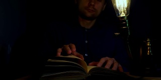 男人在晚上用老式灯看书。