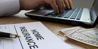 家庭保险表格和经理打字在笔记本电脑上。