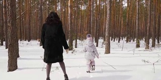 小女孩和妈妈在冬天的森林里奔跑，动作缓慢