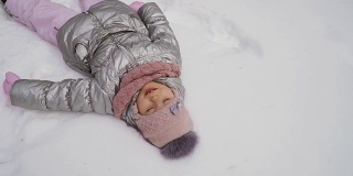 可爱的小女孩躺在雪地上