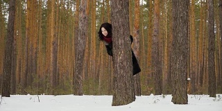 可爱的女人凝视着冬日森林里的树