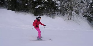 运动女子在松林中的山上滑雪