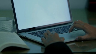 特写的年轻商人使用笔记本电脑/电脑的工作与白色屏幕在办公室有两种色调视频素材模板下载