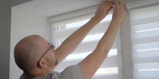 一个男人在公寓窗户上安装新百叶窗的特写镜头