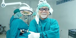 手术室里的资深医生微笑着看着镜头。医疗保健和医疗概念。