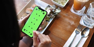 一名女子在绿色屏幕的餐厅使用智能手机
