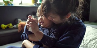 亚洲怀孕家庭在家里的床上聊天和拥抱。