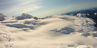 科尔曼冰川冰川雪原后面的舒克山空中飞过阳光明媚的白色北喀斯喀特山脉