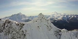 三角形的陡峭岩石的山峰空中飞行近距离看雪山的北方喀斯喀特山和贝克山自然冬季揭示背后的北方喀斯喀特山
