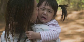 消极情绪亚洲母亲抱着哭泣的女婴在花园
