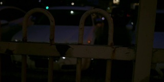 在大都会地区的夜晚，在前景有栅栏的停车场上平移