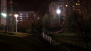 通过混凝土楼梯，穿过昏暗的公园到达公寓大楼视频素材模板下载