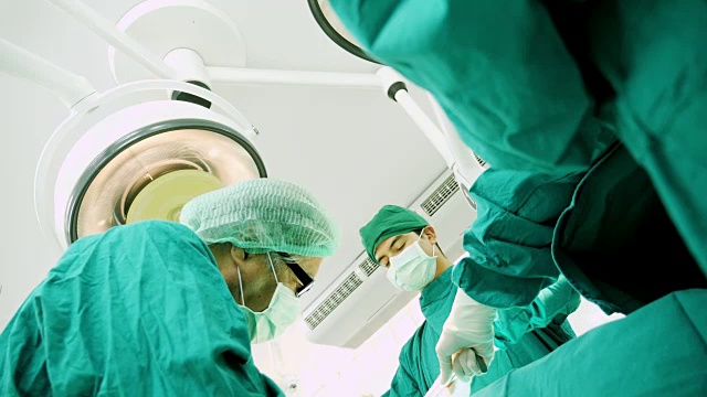 多民族外科手术组穿着防护服在医院手术室进行手术，医疗队在现代手术室进行手术。