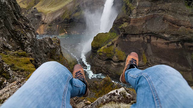 人的个人视角在他的脚上摇摆，坐在峡谷的边缘