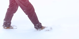 穿着靴子走路的脚在一个冬天的风景中慢动作，一个冬天在山上散步，度假旅游，飘落的雪花