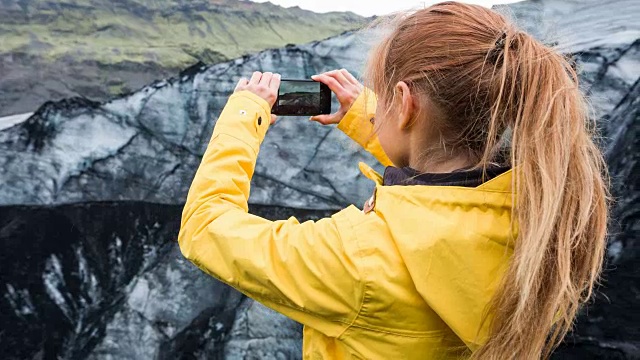 一名妇女正在拍摄被火山灰覆盖的冰川