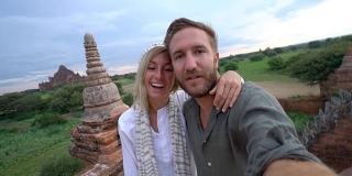 一对夫妇在缅甸一座古老的佛教寺庙上自拍。一对夫妇在缅甸蒲甘探索寺庙，在日出时自拍。一对游客夫妇在亚洲自拍