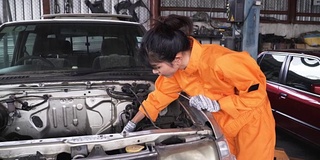 从正面拍摄的小车:亚洲年轻女性汽车技工正在研究汽车发动机