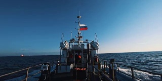 挂着俄罗斯国旗的摩托艇在晴朗的天空下快速驶过海水