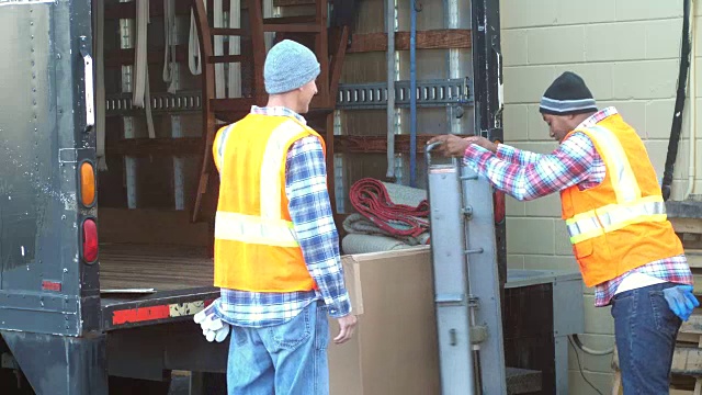 两名工人正在把大箱子装上卡车
