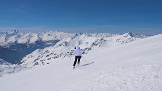 女子在山上以职业滑雪方式滑下斜坡视频素材模板下载