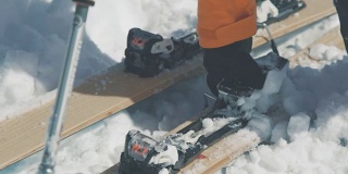 滑雪者的手从滑雪板固定的特写中移除雪