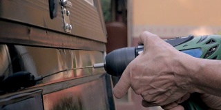 一个手拿着一个无绳钻钻进卡车的后面的特写