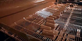 在糖果工厂的生产线上，糖果被浇上巧克力。