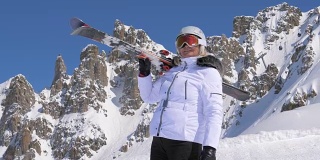 一位肩上扛着滑雪板的女子在山上欣赏大自然的美景