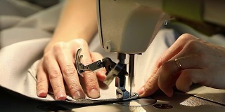 在缝纫机前工作的女人，缝纫机，女性的手，慢动作视频，特写，浅景深，工业缝纫机