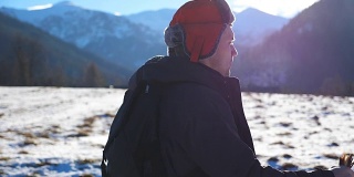 侧面的观点，年轻的徒步旅行者去北欧与棍棒在雪道在野外在山的背景。在阳光明媚的日子里，运动健将在户外运动。健康积极的生活方式。慢镜头