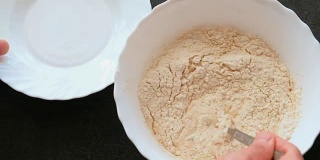 酵母面团的制备。在碗里撒上面粉，加入牛奶和酵母，用叉子混合。