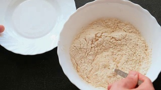 酵母面团的制备。在碗里撒上面粉，加入牛奶和酵母，用叉子混合。视频素材模板下载