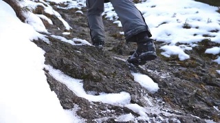 清晨，一个面目全非的人爬上了山道。年轻的男游客走在雪山上。健康积极的生活方式。假日或假期的概念。后视图慢动作视频素材模板下载