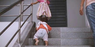 蹒跚学步的婴儿在家里“第一步”爬楼梯