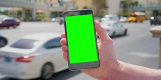 在拉斯维加斯大道附近拿着绿屏智能手机