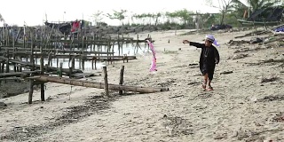 亚洲男孩玩他的传统风筝。他在海滩上跑步。
