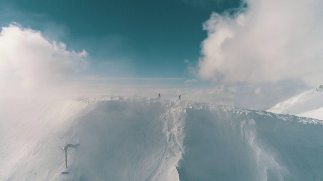 两名滑雪者穿过云层越过山脊的鸟瞰图