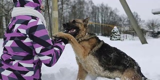 一个穿着冬季夹克的年轻女子抚摸着狗的鼻子。